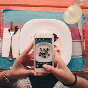 Gast neemt foto van eten op bord in restaurant